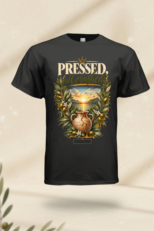 A black short-sleeve t-shirt with a detailed graphic print on the front. The graphic features the text 'PRESSED, NOT CRUSHED' in a gold serif font, above an illustration of a golden sun, a classic clay amphora, olive branches, and gold olives.