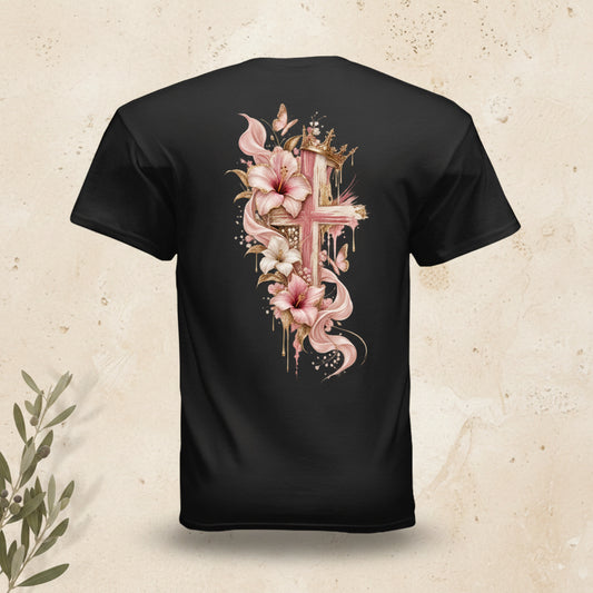 A black short-sleeve t-shirt shown from the back, featuring a large graphic print of a pink and gold cross decorated with pink lilies, white flowers, and gold leaves on a plain white background.
