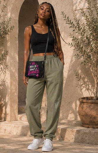 Black crossbody bag worn at hip with purple logo graphic, adjustable strap