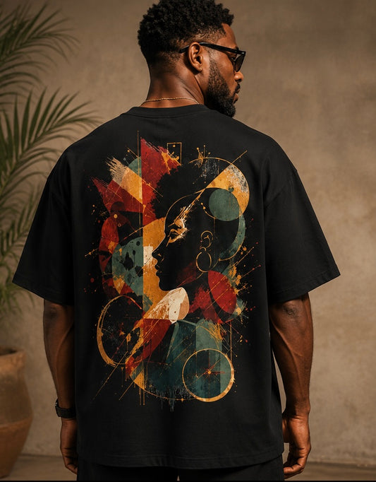 A man wearing a black t-shirt with a large, colorful abstract graphic print on the back, shown from behind in a warm, indoor setting.