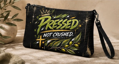 Black zippered crossbody bag front view; 'PRESSED NOT CRUSHED' artwork, side strap
