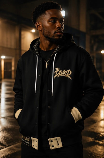 Black hooded zip jacket with white drawstrings, gold chest logo, and beige snap cuffs