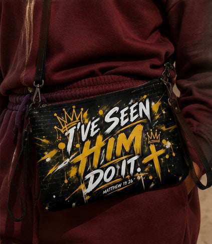 A black crossbody bag with a gold and white graphic print reading 'I've Seen Him Do It. Matthew 18:14' with crowns and a cross, worn crossbody by a person in a maroon sweatshirt.