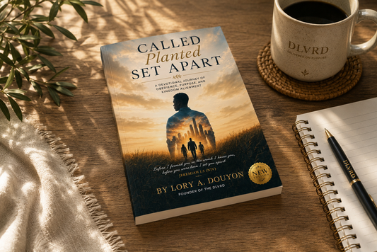 A book titled 'Called Planted Set Apart' by Lory A. Douyon is displayed on a wooden desk next to a coffee mug, a notebook, and a pen, with warm sunlight casting leaf shadows across the scene.