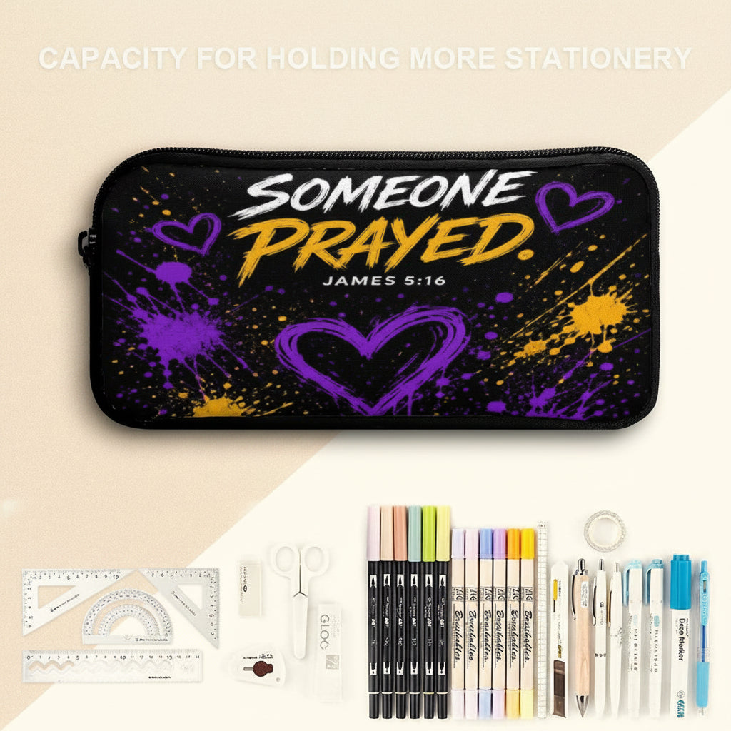 A black zippered pencil case with a purple and yellow heart design and the text 'SOMEONE PRAYED. JAMES 5:16' is shown on a split white and light blue background, with stationery items arranged below it.