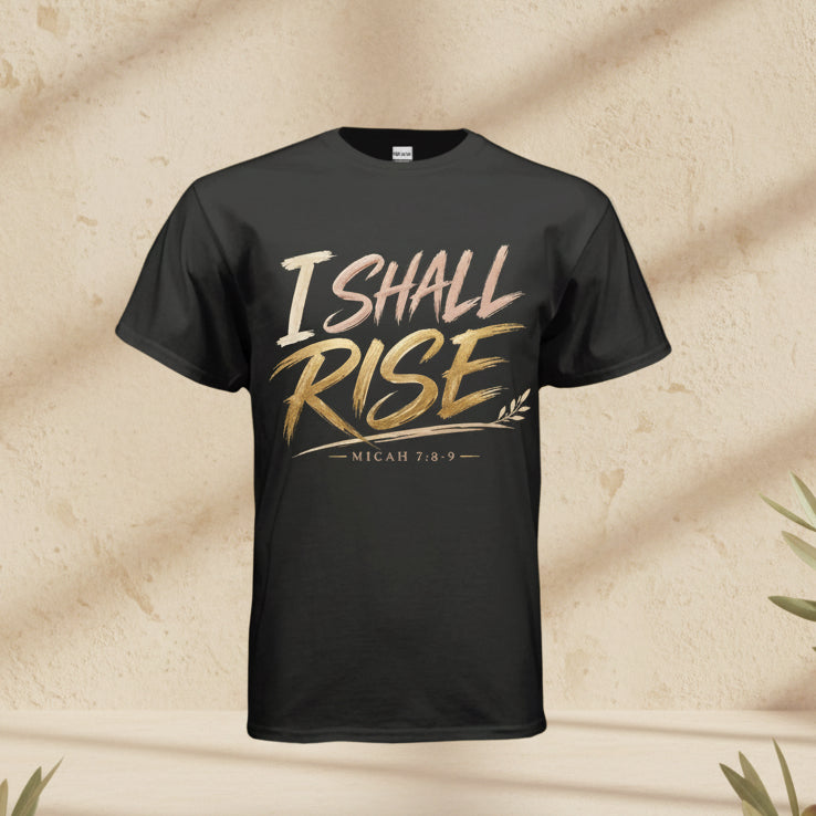 A black short-sleeve t-shirt with a graphic on the chest reading 'I SHALL RISE' in a metallic gold and rose gold gradient, with 'MICAH 7:8-9' printed below, shown against a plain white background.